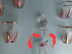 Likör Takımı,  Fransız İmalâtı Altın vermeyli cam Likör takımı, Bardakları hepsinin altında MM ve ters C ve Rakam soğuk damga vardır.  Karaf'ta ağız kısmın da kırık var. 6 adet bardağı ile..Karaf tıpa ile 22 cm. Bardaklar 6 cm..