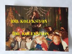 BARIŞ MANÇO'NUN ORİJİNAL FOTOĞRAFI - 17,5 x 12,5 cm EBADINDA - BARIŞ MANÇO, 7'DEN 77'YE PROGRAMINDA, MANÇO KLİP BÖLÜMÜNDE ''BUGÜN BAYRAMİ'' ADLI KLİP ÇEKİMLERİNDE İLKOKUL ÇOCUKLARI İLE AYNI KAREDE, 1980'LER