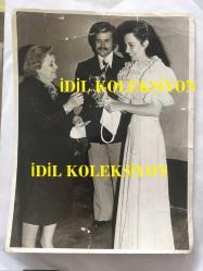 YEŞİLÇAM'IN YILDIZI FATMA GİRİK'İN ORİJİNAL BÜYÜK BOY FOTOĞRAFI - FATMA GİRİK BEYAZ ŞIK BEYAZ ELBİSESİ İÇİNDE KADIN HAKLARINI KORUMA DERNEĞİ BAŞKANI TARAFINDAN GÜMÜŞ KUPA ve HEDİYE VERİLİRKEN ÇEKİLMİŞ GÜZEL BİR FOTOĞRAF, TAMER YİĞİT İLE - 24 x 18 cm EBADINDA - 1970'LER