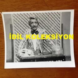 NEJAT UYGUR'UN ORİJİNAL FOTOĞRAFI - 12 x 9,5 cm EBADINDA - SİYAH & BEYAZ - NEJAT UYGUR ÇİZGİLİ CEKETİYLE MASASINDA TİYATRO OYUNU SERGİLERKEN ÇEKİLMİŞ BİR KARE, 12 MART 1992