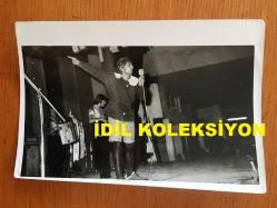 NEJAT UYGUR'UN ORİJİNAL 2'Lİ FOTOĞRAF SETİ - 18 x 13 cm EBADINDA - SİYAH & BEYAZ - NEJAT UYGUR'UN TİYATRO SAHNESİNDE İLKOKUL KIYAFETLERİYLE KONUŞMA YAPTIĞI ANLARDAN 2 FARKLI KARE