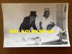 NEJAT UYGUR'UN ORİJİNAL FOTOĞRAFI - 18 x 12 cm EBADINDA - SİYAH & BEYAZ - NEJAT UYGUR OYUN SONRASINDA MİDE KANAMASI GEÇİREN EŞİ NECLA UYGUR'U HASTANEDE HASTA YATAĞINDA YALNIZ BIRAKMADI, VEFA ve SEVGİ DOLU BU DUYGUSAL ANLARDAN BİR KARE, 3 ARALIK 1984