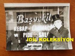 NEJAT UYGUR'UN ORİJİNAL FOTOĞRAFI - 18 x 13 cm EBADINDA - SİYAH & BEYAZ - NEJAT UYGUR SAHNE ÖNCESİNDE YEMEKLERİNİ YEDİĞİ BAŞVEKİL KEBAP, LAHMACUN ve PİDE SALONUNUN ÖNÜNDE SMOKİNİYLE POZ VERİRKEN ÇEKİLMİŞ BİR KARE, 27 KASIM 1984