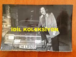 PİYANİST ŞANTÖR YAVUZ ÖZIŞIK'IN ORİJİNAL FOTOĞRAFI - 18 x 12 cm EBADINDA - SİYAH & BEYAZ - YAVUZ ÖZIŞIK 34 LR 606 PLAKALI OTOMOBİLİNİN ÖNÜNE OTURUP POZ VERİRKEN ÇEKİLMİŞ BİR KARE