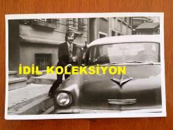 PİYANİST ŞANTÖR YAVUZ ÖZIŞIK'IN ORİJİNAL FOTOĞRAFI - 18 x 12 cm EBADINDA - SİYAH & BEYAZ - YAVUZ ÖZIŞIK KAPISININ ÖNÜNE GELEN BİR TAKSİYE BİNERKEN ÇEKİLMİŞ BİR KARE