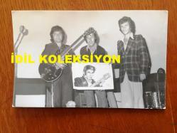 MİLLİ GİTARİST YURDAER DOĞULU'NUN ORİJİNAL 2'Lİ FOTOĞRAF SETİ - 14 x 9 cm EBADINDA - SİYAH & BEYAZ - YURDAER DOĞULU SAHNEDE GİTAR ÇALIP ŞARKI SÖYLERKEN VE ÇİZİLMİŞ BİR PORTRESİNİ ARKADAŞLARIYLA SAHNEDE TUTARKEN ÇEKİLMİŞ 2 FARKLI KARE