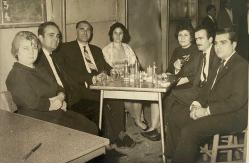 Davette sandalyede oturup gülümseyerek poz veren bir grup kadın ve erkek fotoğrafı. FOTO SARAY .ORİJİNAL SİYAH & BEYAZ, 14 x 9cm EBADINDA - 1940'LAR, 1950'LER, 1960'LAR ve 1970'LER