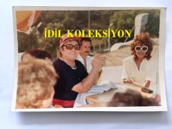 SANAT GÜNEŞİMİZ ZEKİ MÜREN'İN ORİJİNAL 2'Lİ FOTOĞRAF SETİ, - 18 x 12 cm EBADINDA 2 ADET FOTOĞRAF - ZEKİ MÜREN'İN NURHAN DAMCIOĞLU İLE BİRLİKTE BİR KUMSALDA AYNI MASADA OLDUĞU ANLARDAN 2 ÖZEL KARE