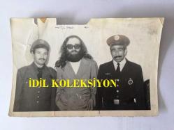 CEM KARACA'NIN ORİJİNAL 2'Lİ FOTOĞRAF SETİ - 18 x 12 cm EBADINDA - SİYAH & BEYAZ - CEM KARACA'NIN TUTUKLANMAK İSTENDİĞİ ANLARDAN 2 FOTOĞRAF, NEDEN TUTUKLANMAK İSTEDİĞİNİ SORAN HAYRANLARINA CEM KARACA BUNUN BİR ŞAKA OLDUĞUNU SÖYLEMİŞTİ...