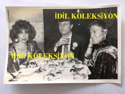 FERDİ ÖZBEĞEN'İN ORİJİNAL FOTOĞRAFI - 18 x 12 cm EBADINDA - FERDİ ÖZBEĞEN, NİL BURAK ve NAZAN ŞORAY İLE AYNI MASADA YEMEK YERKEN ÇEKİLMİŞ BİR FOTOĞRAF,  4 ŞUBAT 1986