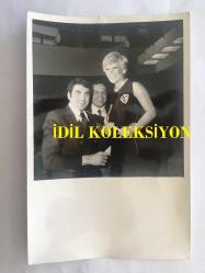 GÖNÜL YAZAR'IN ORİJİNAL FOTOĞRAFI- 18 x 12 cm EBADINDA - GÖNÜL YAZAR, FENERBAHÇE BASKETBOL TAKIMININ VEDA GECESİNDE FERHAN BARAS ve HALİL KONYALI KENDİSİNE FENERBAHÇE ROZETİ TAKARKEN GÜLÜMSÜYOR, SAHNEDEN BİR KARE
