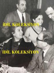 NERİMAN KÖKSAL'IN ORİJİNAL FOTOĞRAFI, 18 x 15 cm EBADINDA - NERİMAN KÖKSAL SEVDİKLERİYLE YEMEK MASASINDA KONUŞURKEN ÇEKİLMİŞ BİR KARE, 1960'LARIN GİYİM TARZI İLE