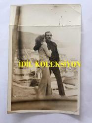 YILDIRIM GENCER'İN ORİJİNAL FOTOĞRAFI - 18 x 12 cm EBADINDA - SİYAH & BEYAZ - YILDIRIM GENCER BİR FİLM SAHNESİNDE SAHİLDE YANINDAKİ KADINA SARILIRKEN ÇEKİLMİŞ BİR KARE