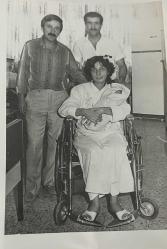 Yeni doğmuş çocuğuyla tekerlekli sandalyeye oturup yakınları ile poz veren yetişkin bir kadın fotoğrafı.ORJİNAL SİYAH & BEYAZ 17x12cm EBADINDA - 1940'LAR, 1950'LER, 1960'LAR ve 1970'LER