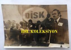 DİSK GENEL BAŞKANI KEMAL TÜRKLER'İN ORİJİNAL FOTOĞRAFI - 18 x 12 cm EBADINDA - KEMAL TÜRKLER, DİSK'İN OLAĞANÜSTÜ GENEL KURUL TOPLANTISINDA AÇILIŞ KONUŞMASI YAPARKEN, 24 EKİM 1976