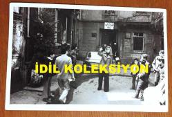 FİLİZ AKIN'IN ORİJİNAL FOTOĞRAFI - 18 x 12 cm EBADINDA - FİLİZ AKIN 1970'LERDE BİR YEŞİLÇAM FİLMİ ÇEKİMLERİNDE 34 NV 968 PLAKALI OTOMOBİLİN ÖNÜNDE SOKAKTAKİ İNSANLARLA KONUŞURKEN