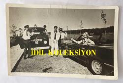 FİLİZ AKIN'IN ORİJİNAL FOTOĞRAFI - 18 x 12 cm EBADINDA - FİLİZ AKIN 1970'LERDE BİR YEŞİLÇAM FİLMİ SAHNESİNDE OTOMOBİL İÇİNDEYKEN KADİR İNANIR'I TUTUKLAYAN POLİSE TABANCA TUTARKEN ''ALMANYALI YARİM (1974)''