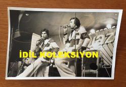 UĞUR BÖCEKLERİ MÜZİK GRUBUNUN ORİJİNAL 2'Lİ FOTOĞRAF SETİ (ZEKİ YURTBAŞI & YALÇIN ÖZDEN) - 18 x 12 cm EBADINDA - ZEKİ YURTBAŞI & YALÇIN SAHNEDE HEM GÜLDÜRÜP HEM DE ŞARKI SÖYLERLERKEN ÇEKİLMİŞ 2 FARKLI KARE