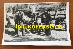 Efemera - ATLARLA İLGİLİ ORİJİNAL BİR FOTOĞRAF - 18 x 12 cm EBADINDA - ZAYIF DÜŞMÜŞ YARALI BİR AT VİNÇLE YERDEN KALDIRILIRKEN OLAYI İZLEYEN HALK OLACAKLARI MERAKLI GÖZLERLE TAKİP EDİYOR.(Sucuk bekleyen müşteriler) - kitantik - kitaLog