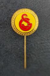 GS/Galatasaray Spor Kulübü Yaka Rozeti (İğneli). Altın Renkli Dairesel Çerçeve İçinde Mineli, Sarı Zemin Üzeri Kırmızı Renkteki GS Logosu İle Kaliteli Bir İşçilik. Koleksiyonluk ve Nadir/Az Çıkar. 1985.