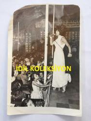 KAMURAN AKKOR'UN ORİJİNAL FOTOĞRAFI - 18 x 12 cm EBADINDA - KAMURAN AKKOR BEYAZ ELBİSESİYLE SAHNEDE ŞARKI SÖYLERKEN (AÇIKLAMAYI OKUYUNUZ)