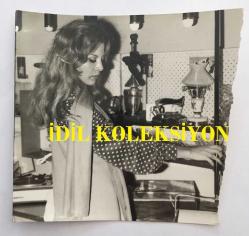 YEŞİLÇAM'IN DEĞERLİ OYUNCUSU HÜLYA TUĞLU'NUN ORİJİNAL FOTOĞRAFI - 12 x 12 cm EBADINDA - HÜLYA TUĞLU EVİNİN MUTFAĞINDA ÇALIŞIRKEN ÇEKİLMİŞ BİR KARE, 1976