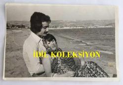 FERİ CANSEL'İN ORİJİNAL FOTOĞRAFI - 18 x 12 cm EBADINDA - FERİ CANSEL SEVGİLİSİYLE DENİZ KENARINDA BİRBİRİNE SARILIRKEN ÇEKİLMİŞ ROMANTİK BİR KARE