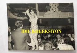 FERİ CANSEL'İN ORİJİNAL 2'Lİ FOTOĞRAF SETİ - 15 x 11 cm ve 14 x 10 cm EBADINDA - FERİ CANSEL ALMANYA'DA SAHNE ALDIĞI BİR MEKANDA MASALARIN ÜZERİNE ÇIKIP DANS EDERKEN ÇEKİLMİŞ 2 FARKLI KARE, 17 OCAK 1978