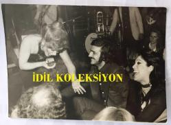 FERİ CANSEL'İN ORİJİNAL FOTOĞRAFI - 15 x 13 cm EBADINDA - FERİ CANSEL SAHNE ALDIĞI MEKANDA TEZGAHTAR SEVGİLİSİNE ŞARKI SÖYLERKEN ÇEKİLMİŞ BİR KARE, KULÜP GALADO