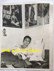 FERİ CANSEL'İN ORİJİNAL BÜYÜK BOY FOTOĞRAFI - 24 x 18 cm EBADINDA - FERİ CANSELLEFKOŞA'DA YEDİĞİ YEMEKLERDEN RAHATSIZLANMASI ÜZERİNE İSTİRAHATE ÇEKİLDİĞİ ODADA DİNLENİRKEN ÇEKİLMİŞ BİR KARE, DUVARDA KENDİ FİLMLERİNİN AFİŞLERİ