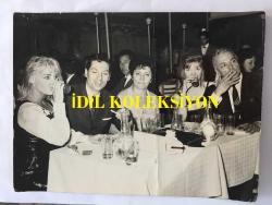 DANSÖZ ve OYUNCU ÖZCAN TEKGÜL'ÜN ORİJİNAL BÜYÜK BOY FOTOĞRAFI - 24 x 18 cm EBADINDA - ÖZCAN TEKGÜL MEKANDA SEVDİKLERİYLE AYNI MASADA VİSKİ İÇERKEN ÇEKİLMİŞ BİR KARE