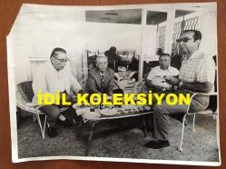 VEHBİ KOÇ'UN ORİJİNAL BÜYÜK BOY FOTOĞRAFI - 24 x 18 cm EBADINDA - VEHBİ KOÇ, BİR DAVETİYEDE KONUKLARLA BİRLİKTE SOHBET EDERKEN ÇEKİLMİŞ BİR KARE, MASADA EFES PİLSEN ŞİŞE BİRALAR