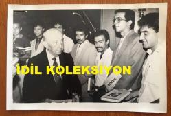 VEHBİ KOÇ'UN ORİJİNAL FOTOĞRAFI - 18 x 12 cm EBADINDA - VEHBİ KOÇ, TEV BURSUYLA ABD'DE MASTER ÖĞRENİMİ GÖRECEK 14 ÖĞRENCİYE ''HAYAT HİKAYEM'' ADLI KİTABINI HEDİYE VERİRKEN ÇEKİİLMİŞ BİR KARE, 1985
