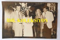 TÜRK SANAT MÜZİĞİ SANATÇISI SEVİM TUNA'NIN AJANS BASIMI FOTOĞRAFI (KAĞIT BASKI) - 18 x 12 cm  EBADINDA - SEVİM TUNA DÜĞÜNDE GELİN ve DAMATLA HATIRA POZU VERİRKEN ÇEKİLMİŞ BİR KARE