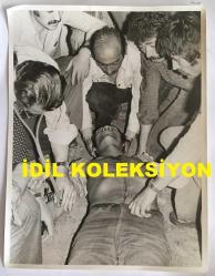 TÜRKİYE CUMHURİYETİ ESKİ BAŞBAKANI BÜLENT ECEVİT'İN OLAYLI GEREDE MİTİNGİNİN ORİJİNAL AJANS-BASIN BÜYÜK BOY FOTOĞRAFI - 24 x 18 cm EBADINDA - BÜLENT ECEVİT'İN GEREDE MİTİNGİNDE MEYDANA GELEN OLAYLARDA ÇEKİLMİŞ BİR KARE, HAZİRAN 1975 - OLAYLARDA YARALANAN BİR GENCE CHP'NİN ADIYAMAN MİLLETVEKİLİ DOKTOR KEMAL TABAK İLKYARDIM MÜDAHALESİ YAPARKEN ÇEKİLMİŞ NET KALİTEDE BİR FOTOĞRAF