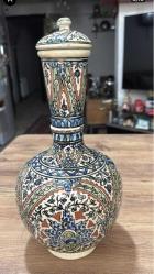ESKİ DEKORLUK KÜTAHYA ÇİNİ ŞİŞE SÜRAHİ Dışa dönük düz ağızlı, pedestal ayaklı, küresel gövdeli ve kapaklı şişenin yüzeyi kobalt mavi, yeşil, sarı, kiremit kırmızısı ve turkuaz ile hayati, şakayık, sümbül, mine ve rozet çiçekleri ile dekorlu.  Dönem: 20. yüzyıl sonları Yükseklik 34 cm