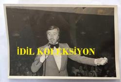 TÜRK HALK MÜZİĞİ SANATÇISI AHMET SEZGİN'İN ORİJİNAL FOTOĞRAFI - 18 x 12 cm EBADINDA - AHMET SEZGİN SAHNEDE TÜRKÜ OKURKEN ÇEKİLMİŞ BİR KARE