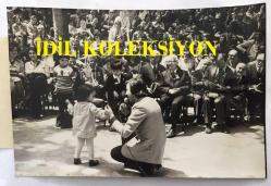 TÜRK HALK MÜZİĞİ SANATÇISI AHMET SEZGİN'İN ORİJİNAL FOTOĞRAFI - 18 x 12 cm EBADINDA - AHMET SEZGİN, İSTANBUL ERKEK LİSESİ'NİN 92. KURULUŞ YILDÖNÜMÜ KUTLAMALARINDA VERDİĞİ KONSERDE 2 YAŞINDAKİ BİR KIZ ÇOCUĞUYLA SAHNEDE OYNARKEN ÇEKİLMİŞ BİR FOTOĞRAF (ATİLLA DAĞLI, 16 MAYIS 1976)
