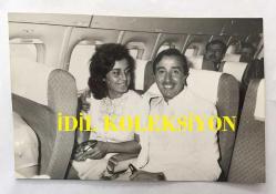 TÜRK HALK MÜZİĞİ SANATÇISI AHMET SEZGİN'İN ORİJİNAL FOTOĞRAFI - 18 x 12 cm EBADINDA - AHMET SEZGİN EŞİ MİNE SEZGİN'LE BİRLİKTE UÇAKTA SEYAHAT EDERKEN ÇEKİLMİŞ BİR HATIRA FOTOĞRAFI