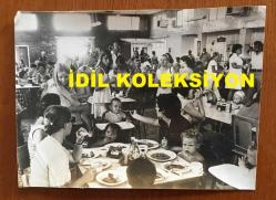 KIBRIS BARIŞ HAREKATI SÜRECİNDE KIBRIS'TAN ÇIKARILAN İNGİLİZ ve DİĞER YABANCI TURİSTLERİN ORİJİNAL AJANS-BASIN FOTOĞRAFI - 20 x 15 cm EBADINDA - KAPALI BİR YERDE TOPLUCA YEMEK YİYEN TURİST AİLELER