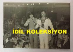 TÜRK HALK MÜZİĞİ SANATÇISI YILDIRAY ÇINAR'IN ORİJİNAL FOTOĞRAFI - 11 x 7,5 cm EBADINDA - YILDIRAY ÇINAR KONSER VERDİĞİ SAHNEYE GELEN BİR HAYRANINA MİKROFON UZATIP TÜRKÜ OKUTURKEN ÇEKİLMİŞ BİR KARE