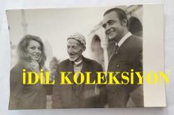 SEVTAP ÇETİNKALE'NİN ORİJİNAL FOTOĞRAFI - 14 x 9 cm EBADINDA - SEVTAP ÇETİNKALE, SEVGİLİSİ BÜLENT ORAL'LA BİRLİKTE MEVLANA TÜRBESİNİN ÖNÜNDE YAŞLI BİR AMCAYLA SOHBET EDERKEN ÇEKİLMİŞ BİR KARE. FOTO AR. KONYA