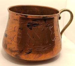 Üzerinde elle yapılmış işlemeler olan pirinç saplı bakır kap