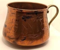 Üzerinde elle yapılmış işlemeler olan pirinç saplı bakır kap