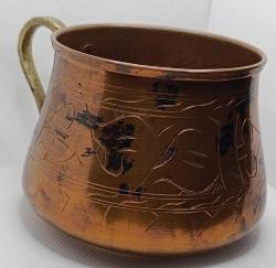 Üzerinde elle yapılmış işlemeler olan pirinç saplı bakır kap