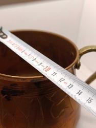 Üzerinde elle yapılmış işlemeler olan pirinç saplı bakır kap