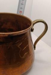 Üzerinde elle yapılmış işlemeler olan pirinç saplı bakır kap