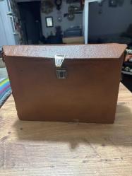 Vintage Kahverengi Evrak Çantası Eski dönemden kalma kahverengi suni deri evrak çantası. Metal kilidi çalışır durumda, genel durumu iyi. Yaklaşık 1960–1980 yılları arası üretimdir. Koleksiyon, dekor veya günlük kullanım için uygundur. Taşıma kayışı yok Ölçüleri Uzunluk 34 cm En 12,5cm Yükseklik 24 cm