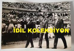 TÜRK HEKİM ve SİYASETÇİ, 1968-1973 İSTANBUL BELEDİYE BAŞKANI DOKTOR FAHRİ ATABEY'İN ORİJİNAL FOTOĞRAFI - 18 x 12 cm EBADINDA - DR. FAHRİ ATABEY, 19 MAYIS GENÇLİK ve SPOR BAYRAMI GÜNÜ DOLMABAHÇE MİTHATPAŞA STADYUMUNDA DÜZENLENEN KUTLAMALAR SIRASINDA İSTANBUL VALİSİ VEFA POYRAZ ve GARNİZON KOMUTANI KORGENERAL FİKRET GÖKNAR'LA BİRLİKTE YÜRÜYÜP HALKI SELAMLARKEN ÇEKİLMİŞ BİR KARE