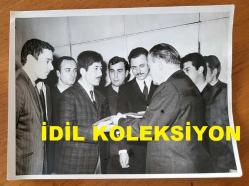 TÜRK HEKİM ve SİYASETÇİ, 1968-1973 İSTANBUL BELEDİYE BAŞKANI DOKTOR FAHRİ ATABEY'İN BÜYÜK BOY ORİJİNAL FOTOĞRAFI - 24 x 18 cm EBADINDA - DR. FAHRİ ATABEY, KENDİSİNİ ZİYARETE GELEN TÜRK MİLLİ TALEBE BİRLİĞİ (MTTB) ÜYESİ GENÇLERDEN TÜRK BAYRAĞI ALIRKEN ÇEKİLMİŞ BİR KARE